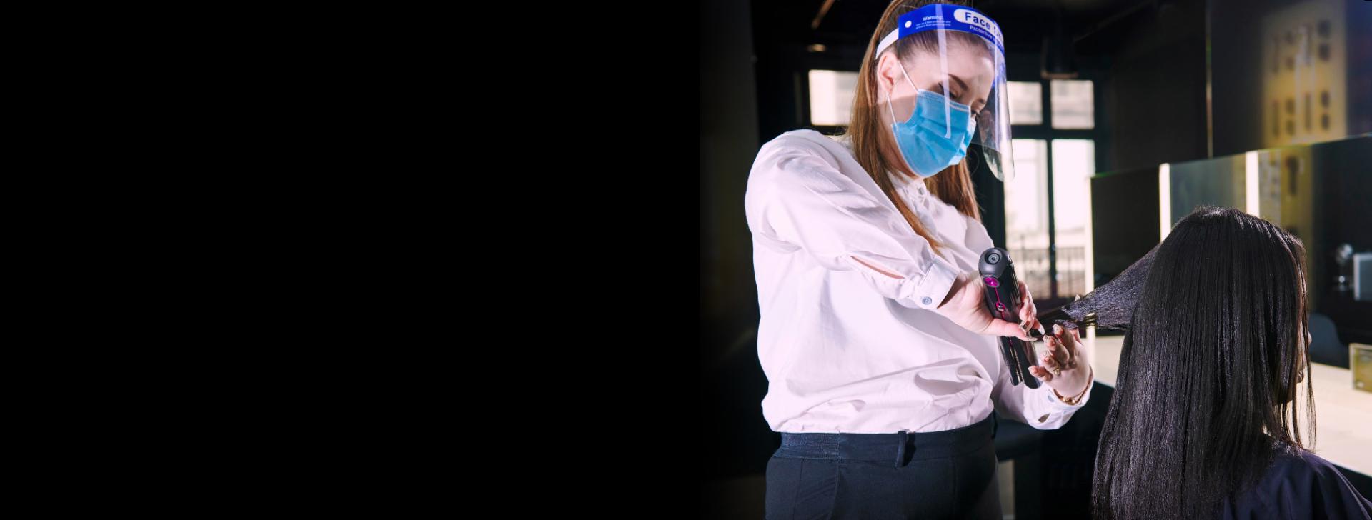 매장 내 고객과 다이슨 코랄 헤어 스트레이트너를 사용하는 스타일리스트