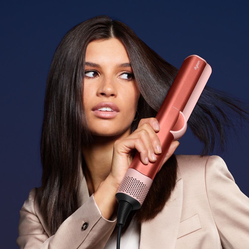The Dyson Airstrait straightener is used by a model to style her hair.
