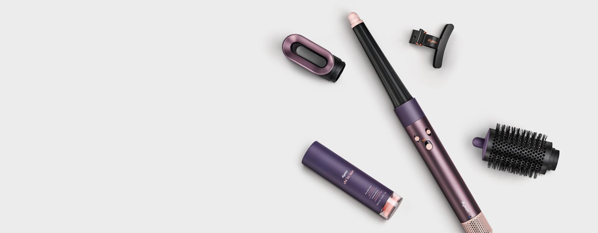 The Dyson Airwrap i.d. multi-styler and dryer in Jasper plum surrounded by attachments and accessories.