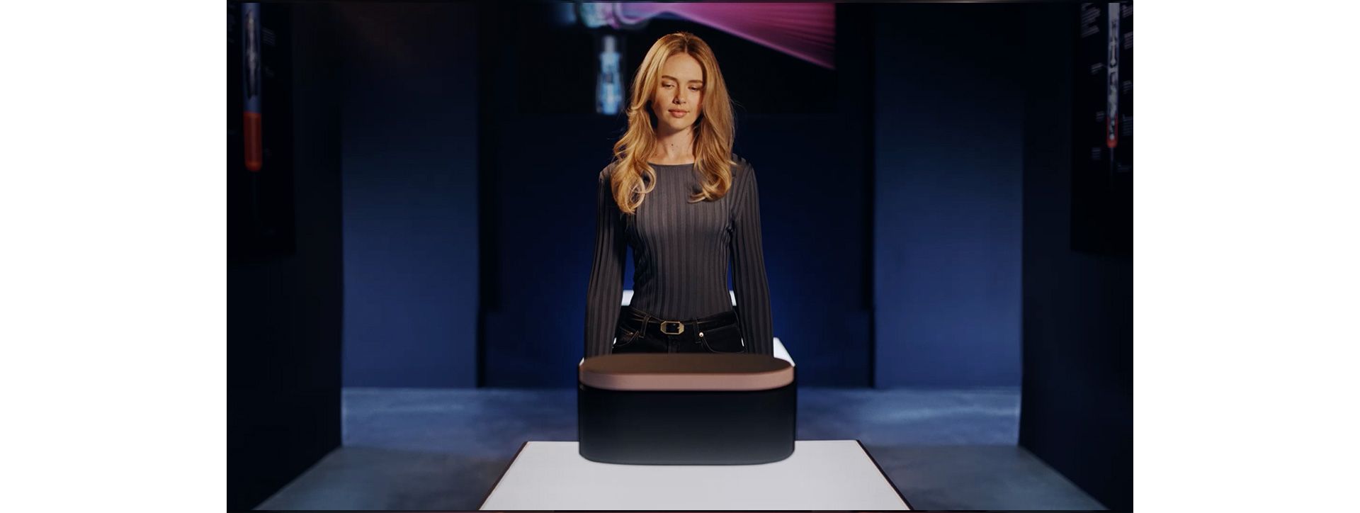A woman opens a presentation case in a Dyson Store, a pink glow lights up her face