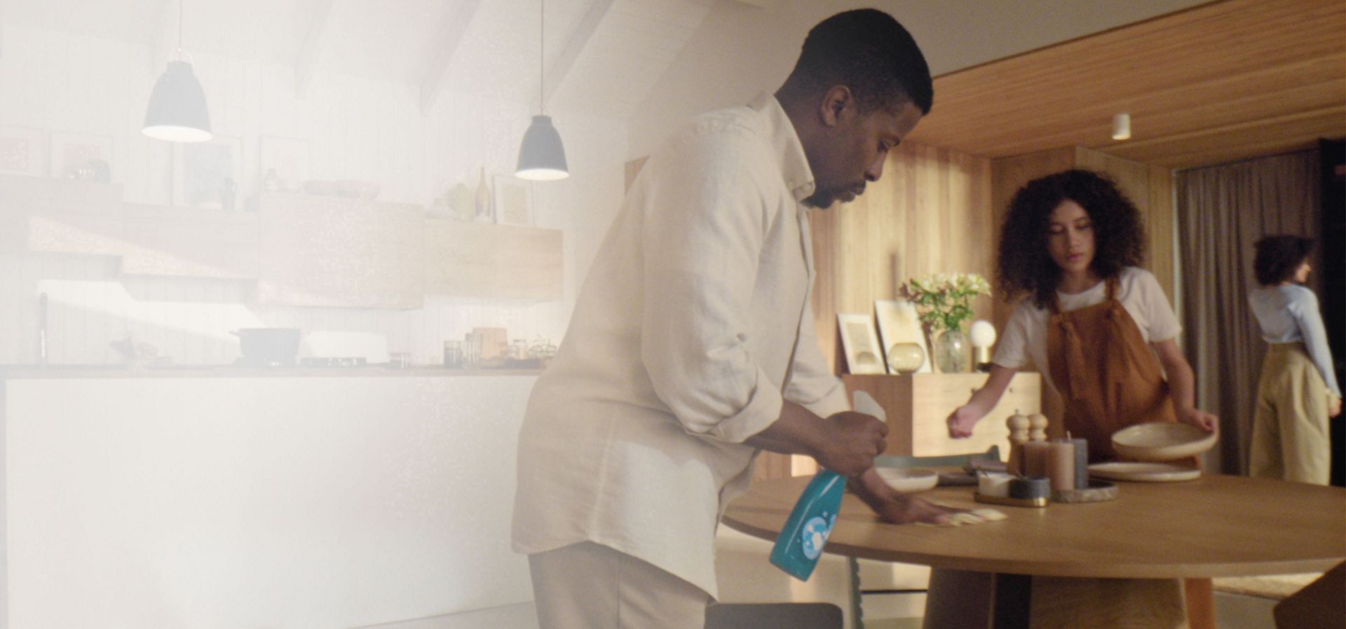 一名男士在用餐前，於現代化的開放式廚房與起居空間中噴灑清潔用品。