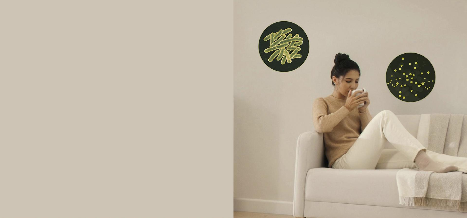 A woman is shown on her sofa with two roundels of bacteria and viruses surrounding her.