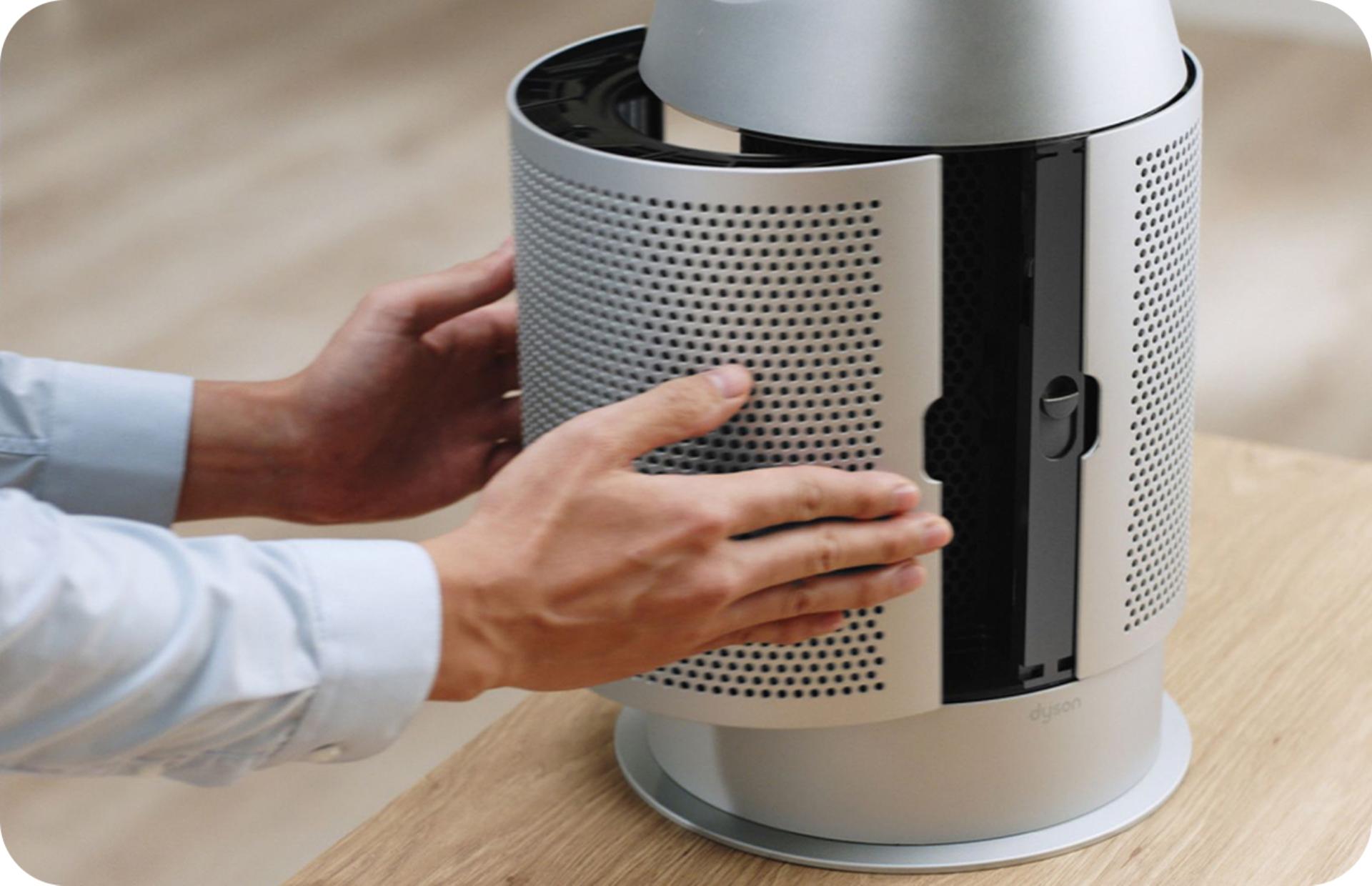 A close-up of a person opening up the body of a Dyson air purifier