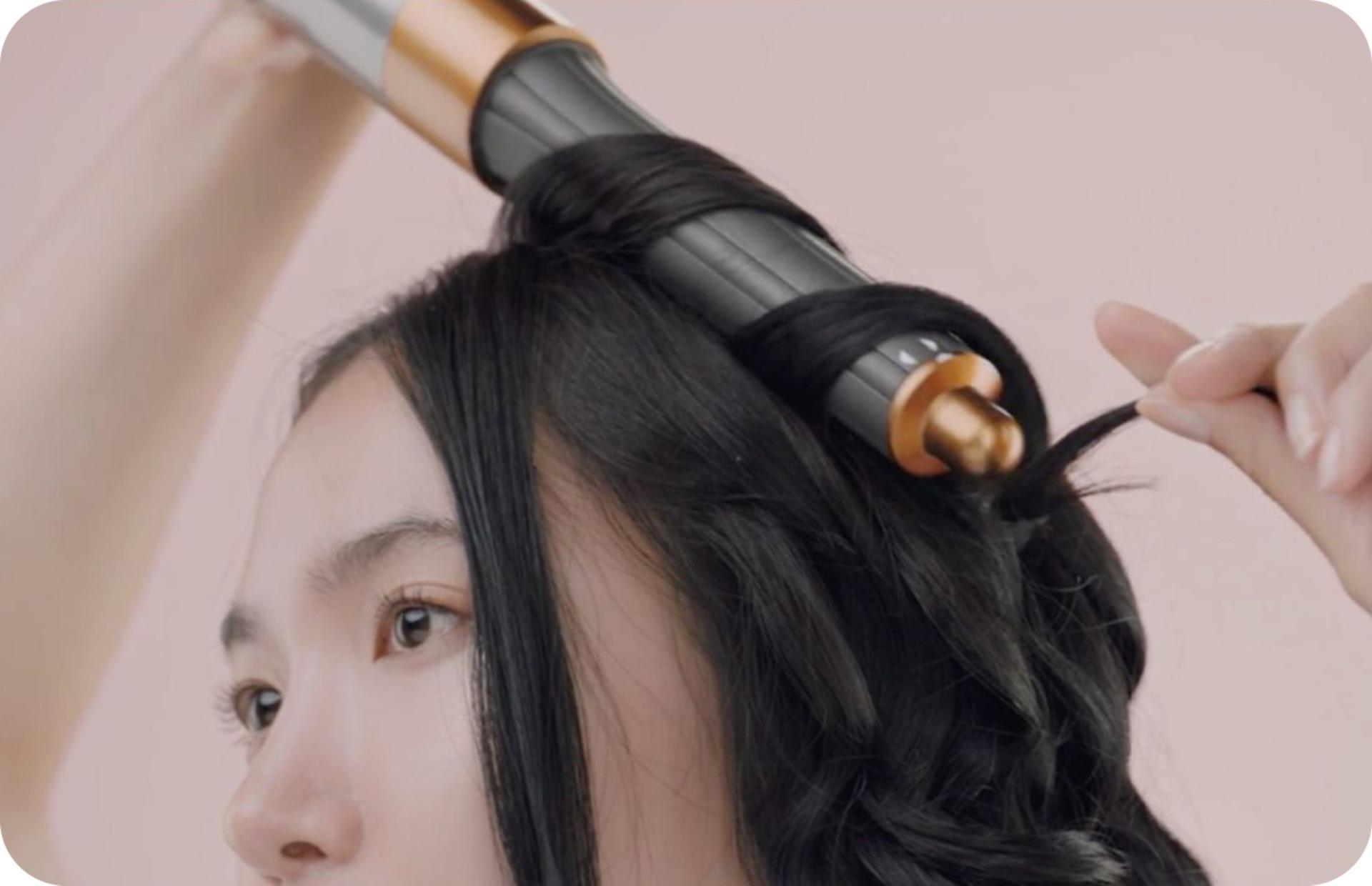 A cropped shot of a woman curling her hair with a Dyson Airwrap™