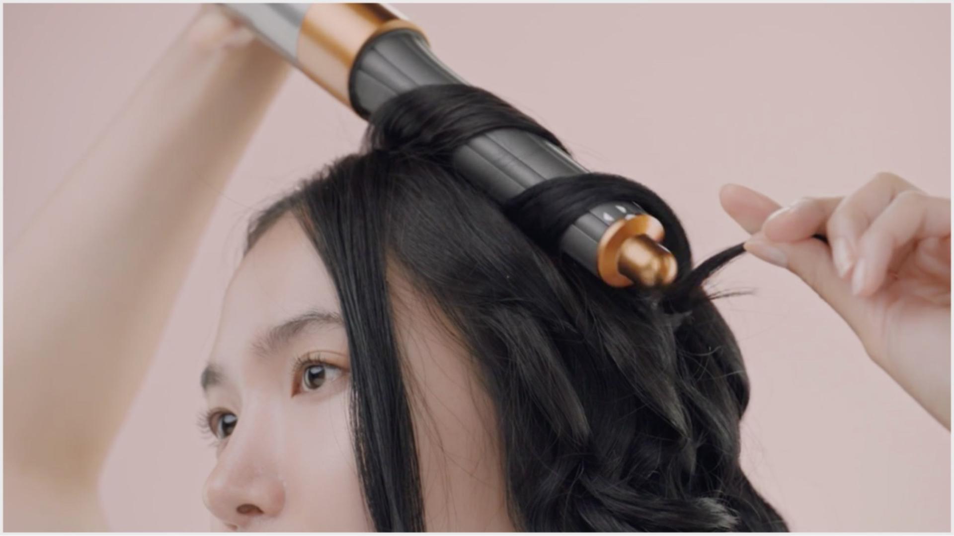 Woman styling hair with Dyson hair care technology.