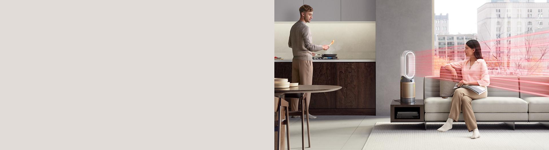 The Dyson Purifier Hot+Cool Formaldehyde in a living room while a couple cook and relax.
