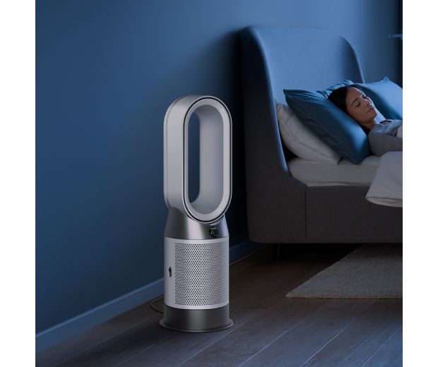 A Dyson Purifier Hot+Cool Gen1 purifying fan heater purifies the air next to a sleeping person.