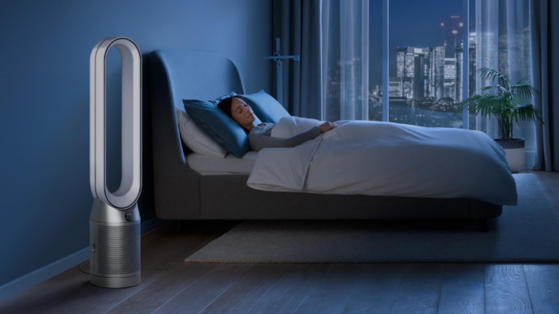 A Dyson Purifier Cool in Night mode next to a sleeping person.