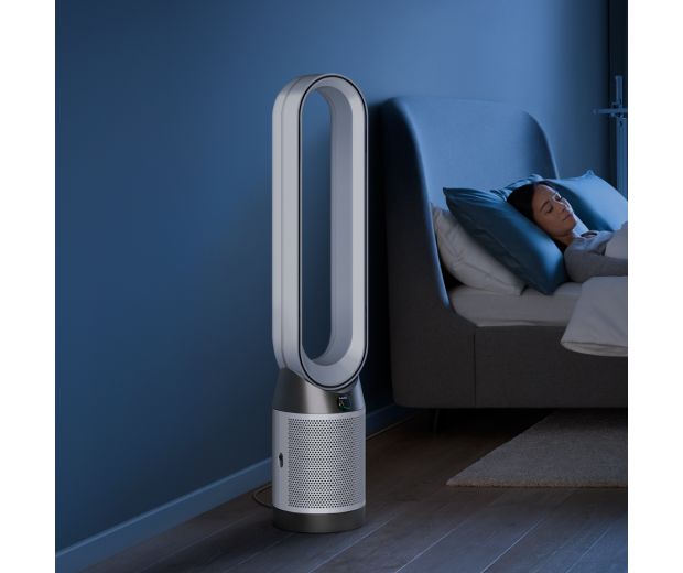 A Dyson Purifier Cool Gen1 TP10 purifying fan operates next to a person asleep in a bed.