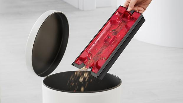 Emptying the debris tray into a bin.