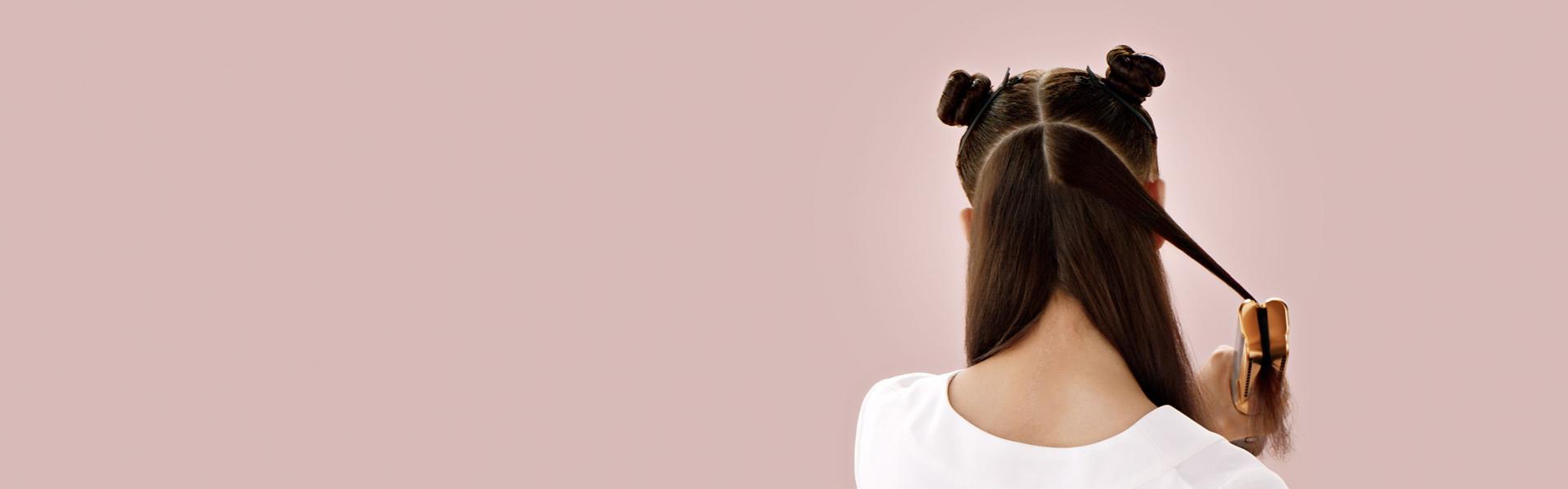 Model with long brown hair straightens her hair in layers with the Dyson Airstrait straightener.