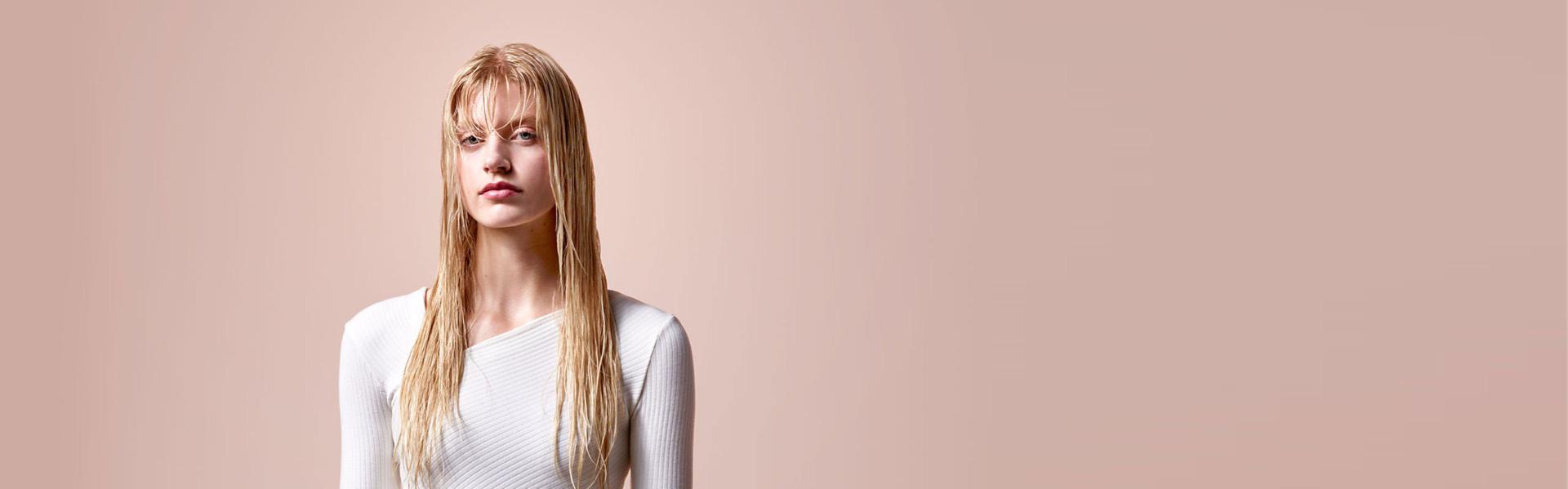 عارِضة تظهر شعرها الأشقر الطويل والرطب قبل تمليسه.