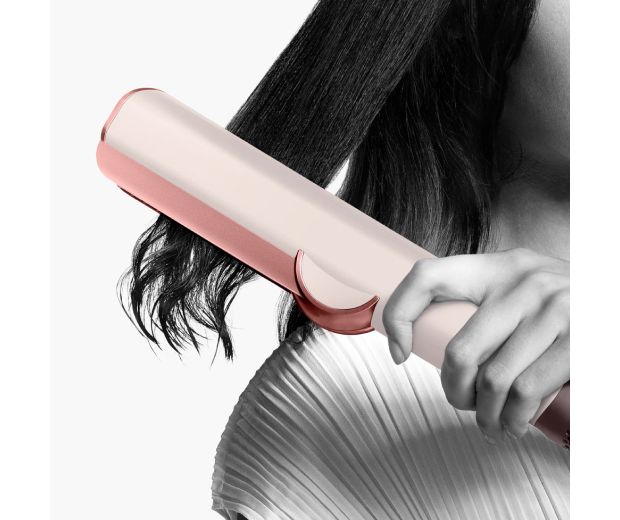 Close-up of the Dyson Airstrait straightener straightening long black hair.