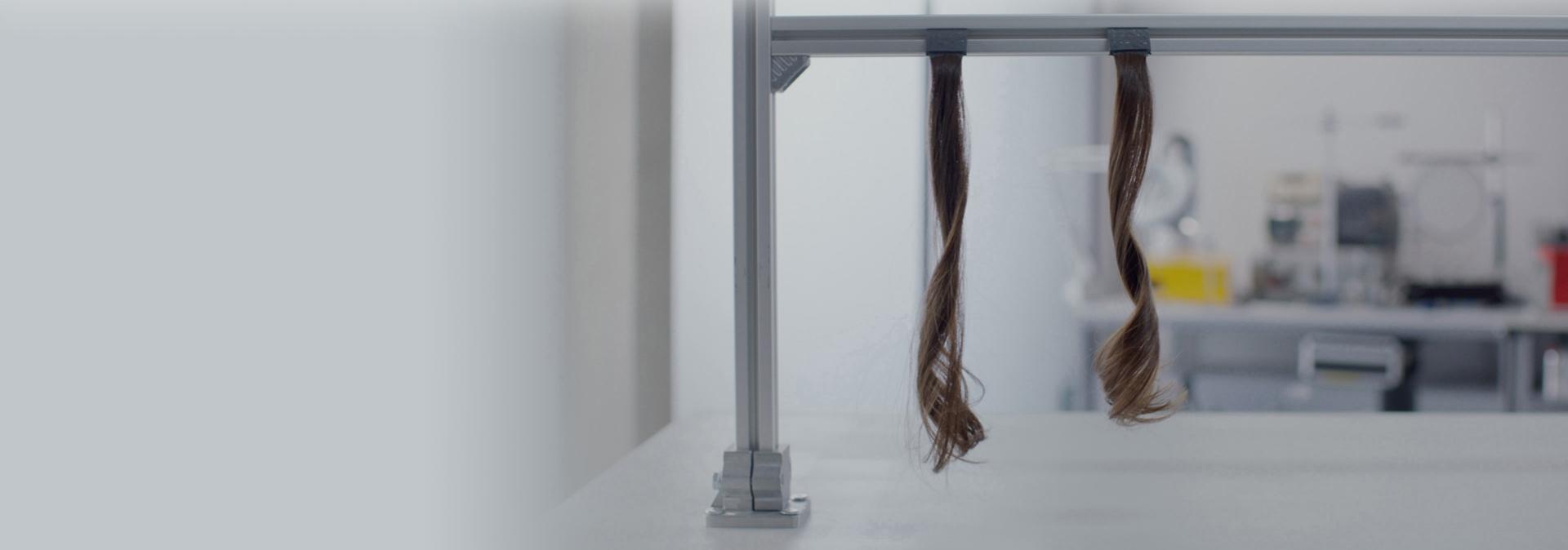 Two sections of hair hang up in a Dyson lab.