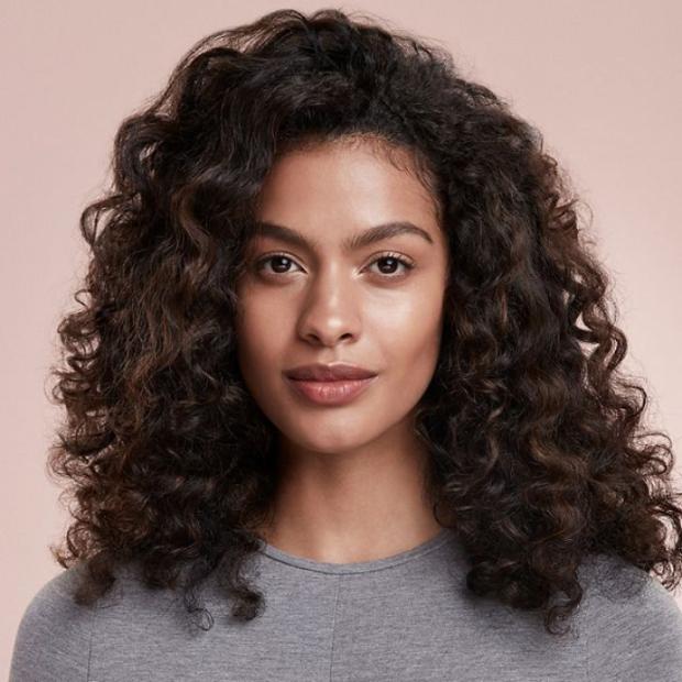 Model with brown hair shows off her hair’s defined curls and waves.