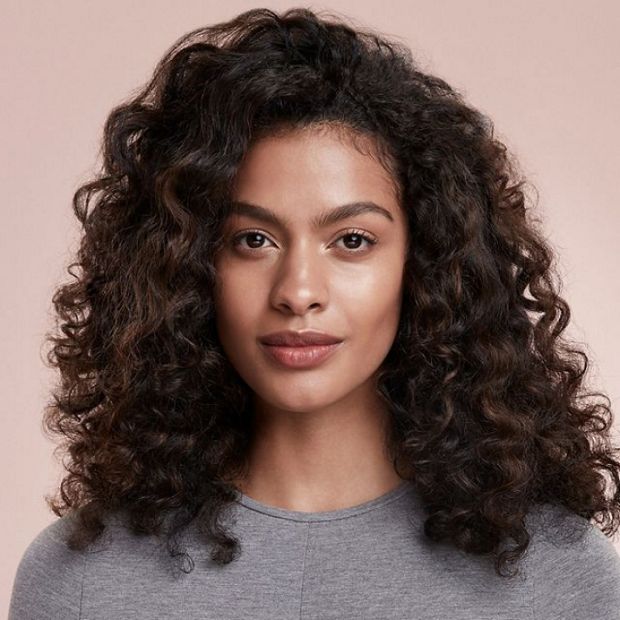 Model with brown hair shows off her hair’s defined curls and waves.