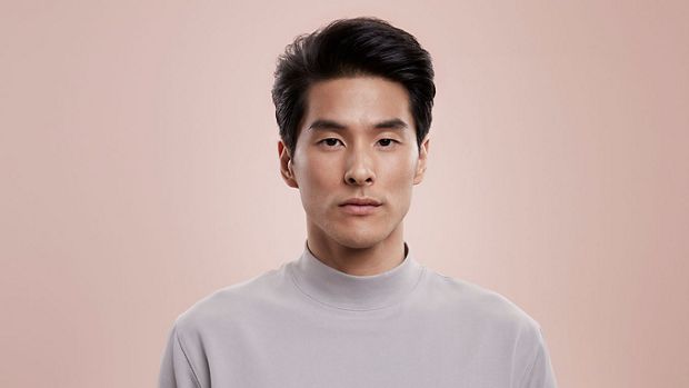 A dark-haired male model with a voluminous textured hair style.