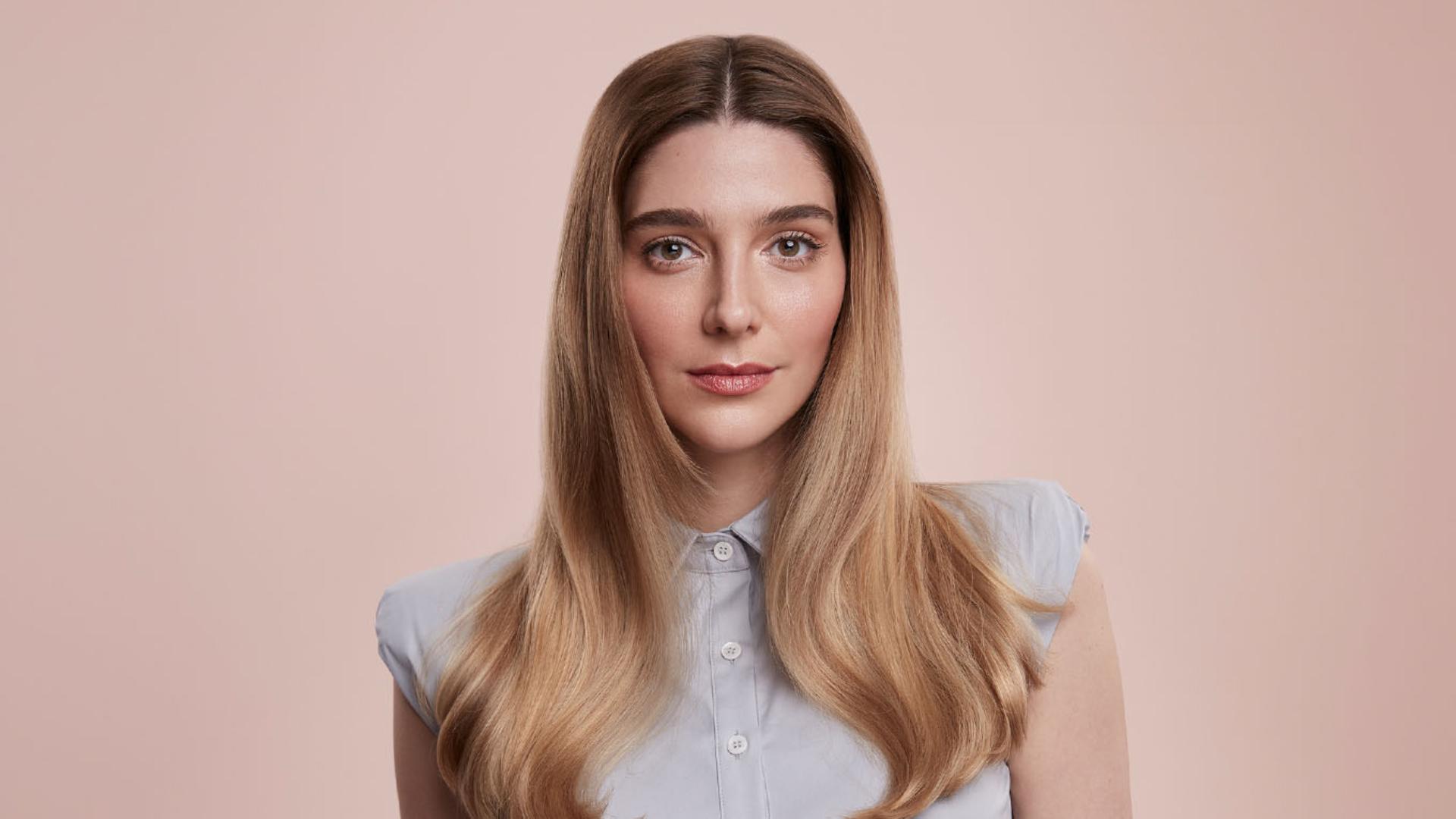 Blond modelka z długimi włosami ułożonymi w gładką fryzurę.