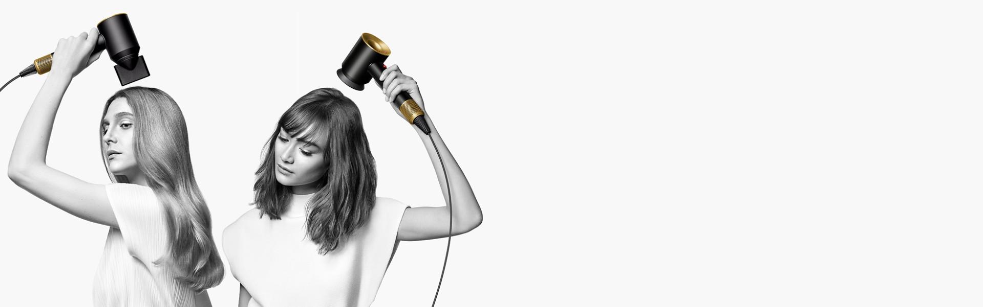 سيدتان تقومان بتجفيف شعرهما باستخدام مجفف الشعرDyson Supersonic. تَستخدم السيدة على اليسار ملحق إخفاء الشعر المتطاير لتنعيم شعرها الطويل المالس، بينما تَستخدم السيدة على اليمين ملحق مُوزِّع الهواء لتشكيل شعرها القصير الملفوف.