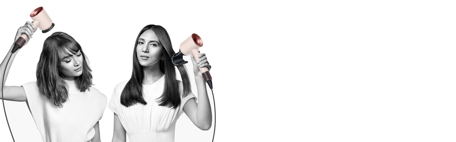 سيدتان تقومان بتجفيف شعرهما باستخدام مجفف الشعرDyson Supersonic. تَستخدم السيدة على اليسار ملحق إخفاء الشعر المتطاير لتنعيم شعرها الطويل المالس، بينما تَستخدم السيدة على اليمين ملحق مُوزِّع الهواء لتشكيل شعرها القصير الملفوف.