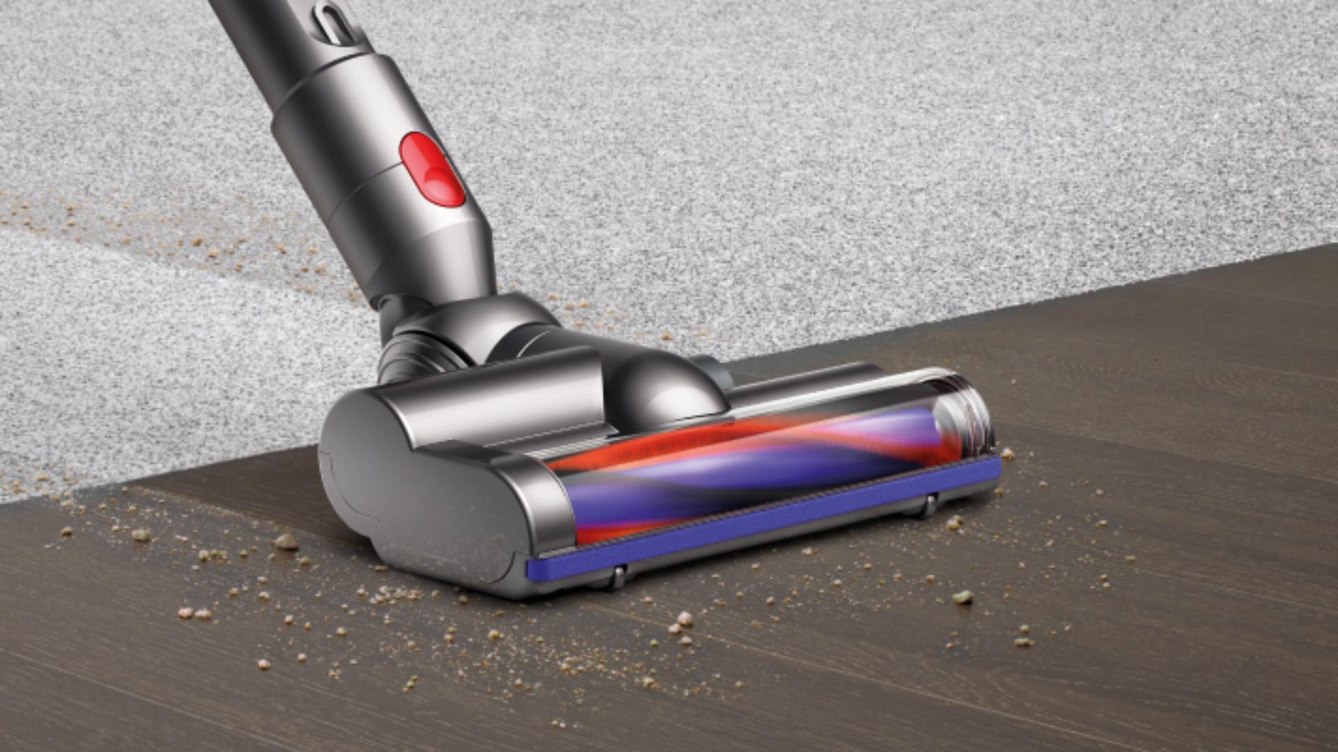 Prim-plan al capătului cu turbină îndepărtând resturi de pe covor și pardoseală dură.