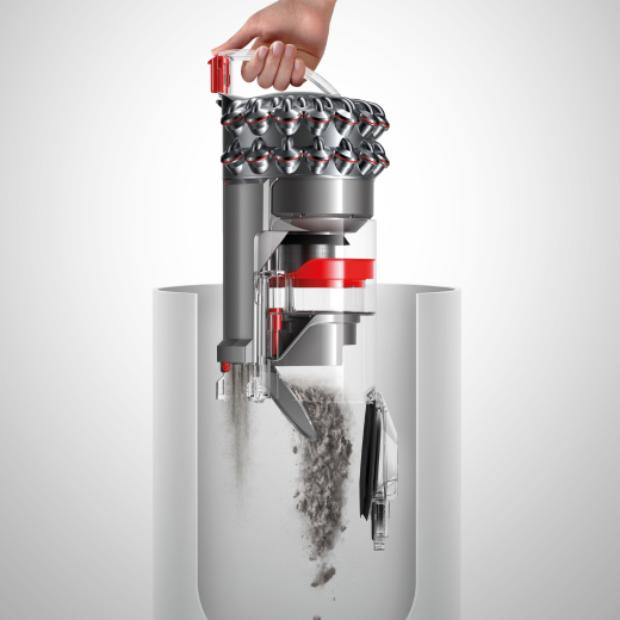 Egy személy úgy üríti ki a hagyományos porszívó portartályát, hogy nem ér hozzá a koszhoz.