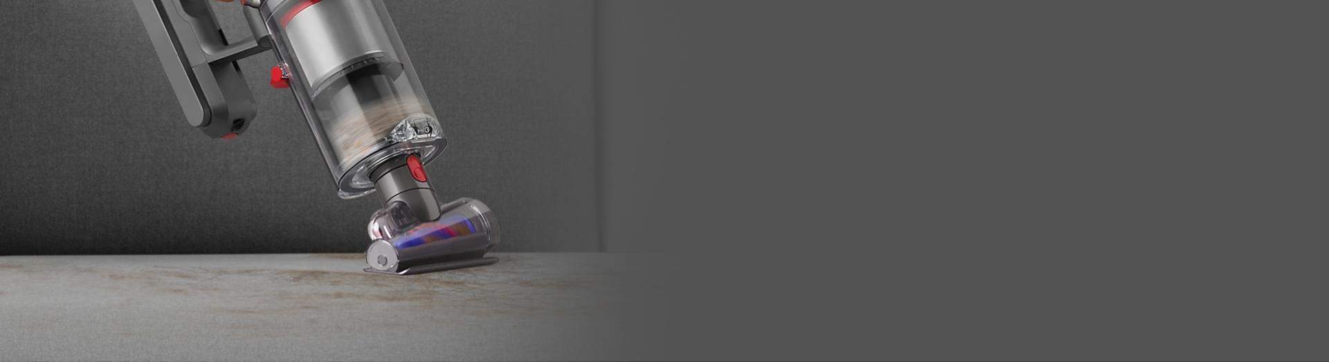 مكنسة Dyson Gen5detect بينما تقوم بتنظيف المفروشات في الوضعية المحمولة مع أداة لف الشعر مركّبة.