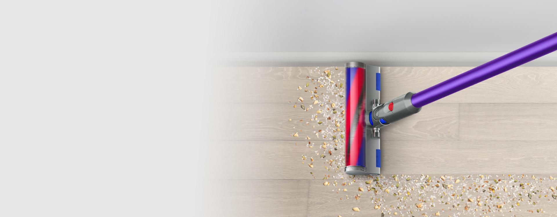 The Dyson V12 Detect Slim Absolute with Fluffy Optic cleaner head illuminating dirt on hard floor.