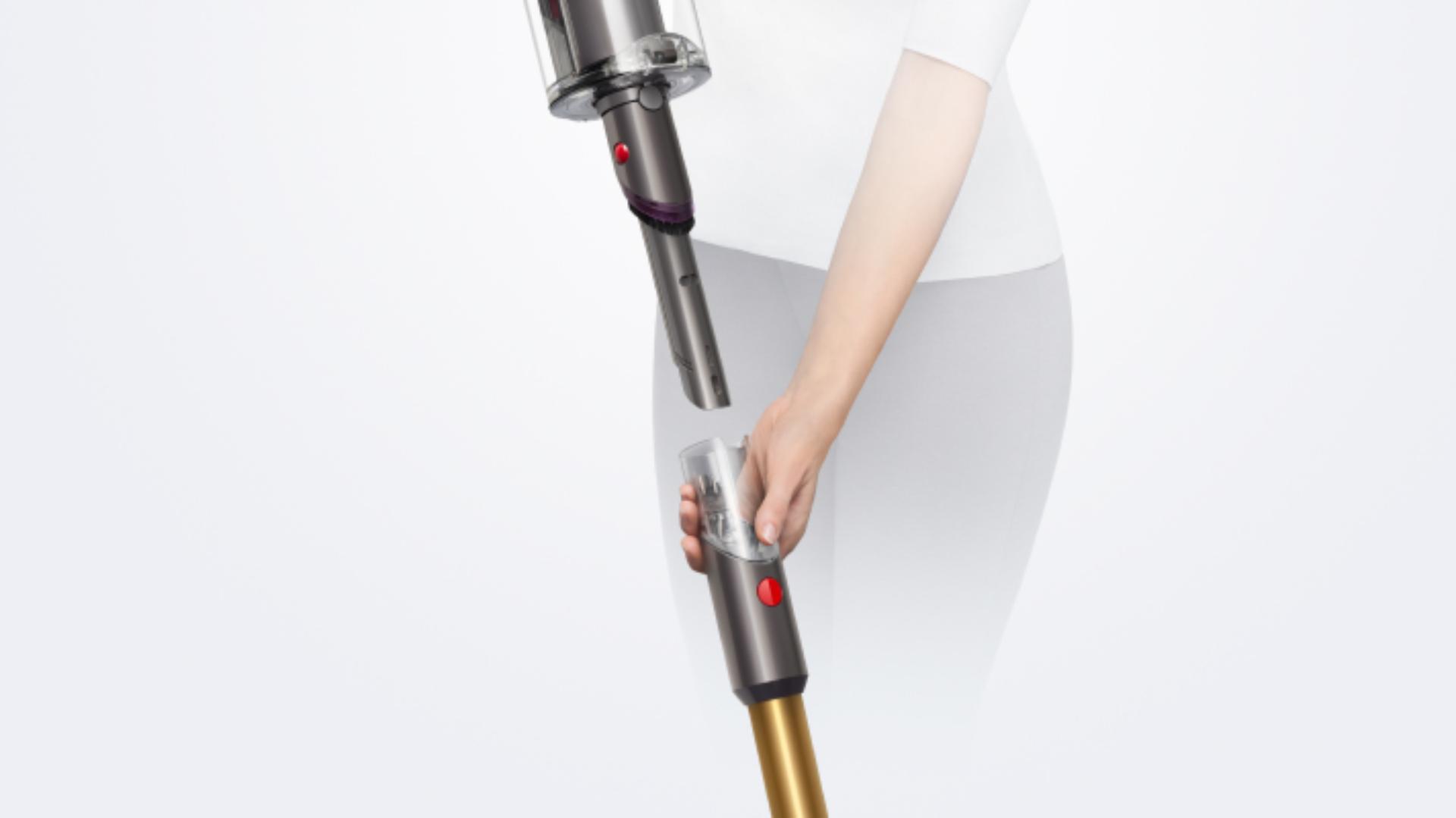 Dyson V15 Detect kablosuz süpürgenin borusunu ayırarak Entegre toz alma ve aralık temizleme başlığını ortaya çıkaran bir kadın.