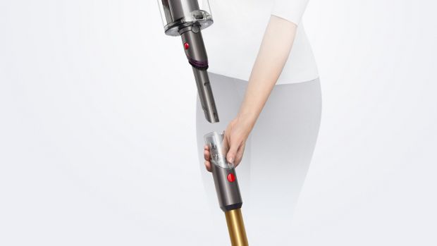 A woman removes the wand on the Dyson V15 Detect vacuum to reveal the Built-in dusting and crevice tool.