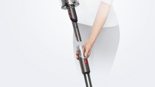 A woman removes the wand on the Dyson V15 Detect vacuum to reveal the Built-in dusting and crevice tool.