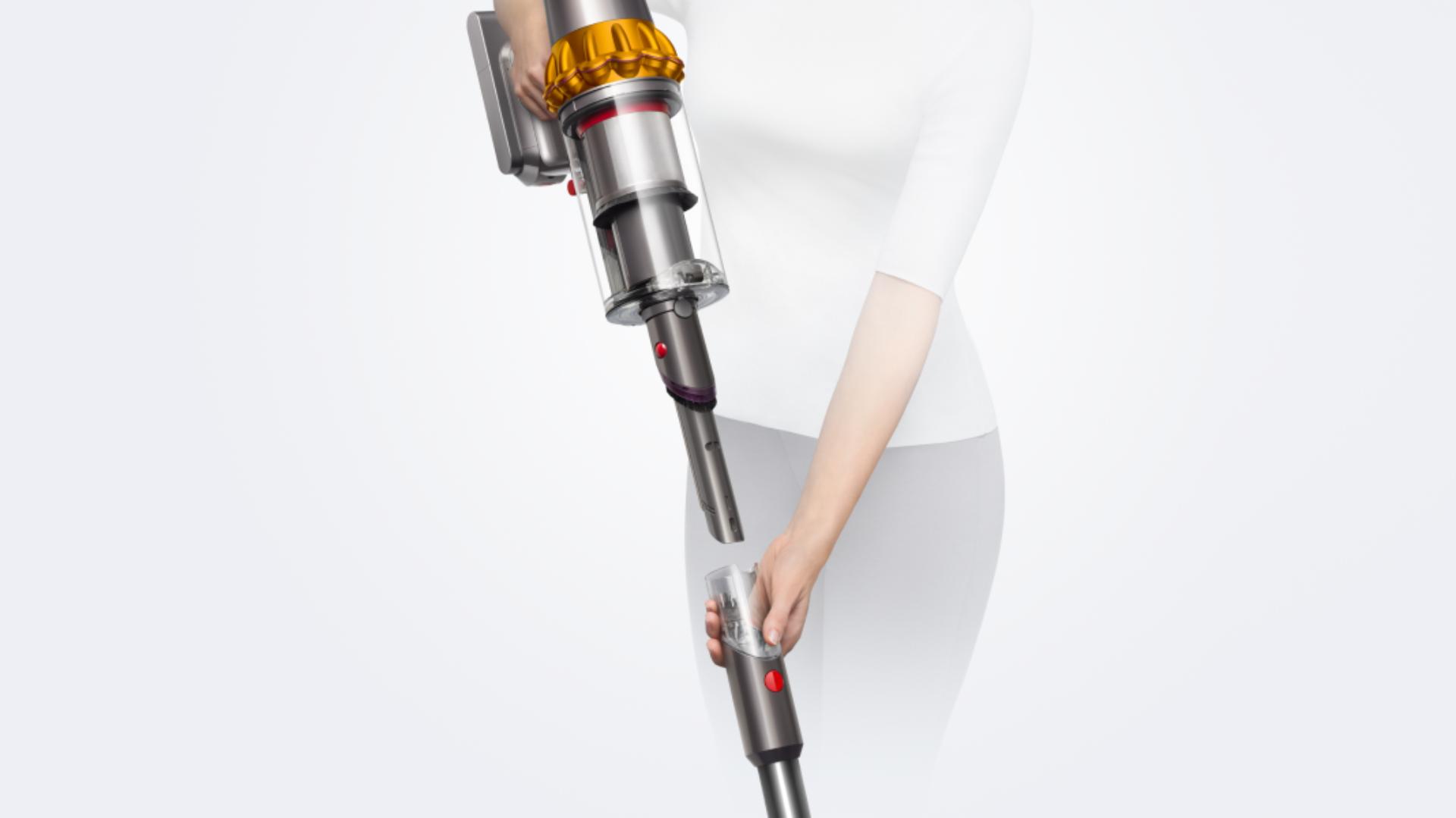 A woman removes the wand on the Dyson V15 Detect vacuum to reveal the Built-in dusting and crevice tool.