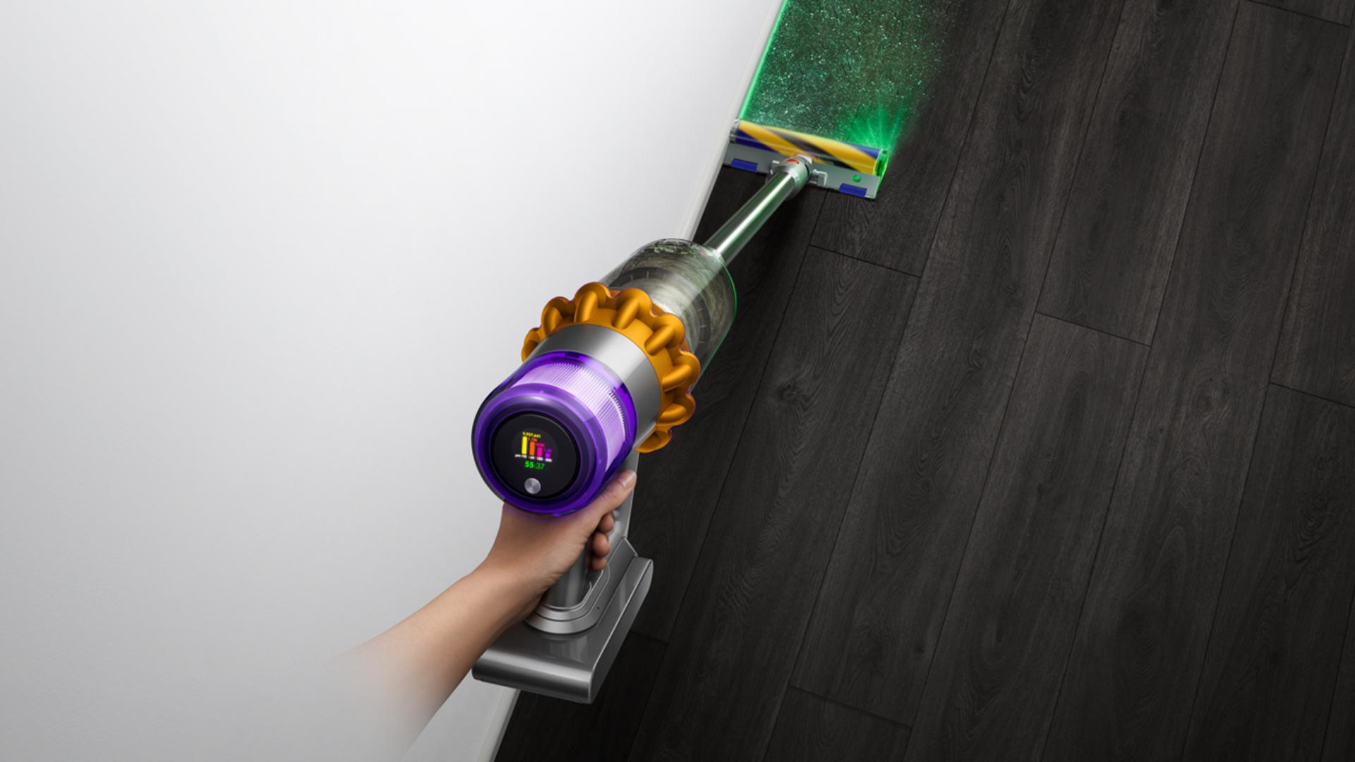 A person using a Dyson vacuum to clean the floor.