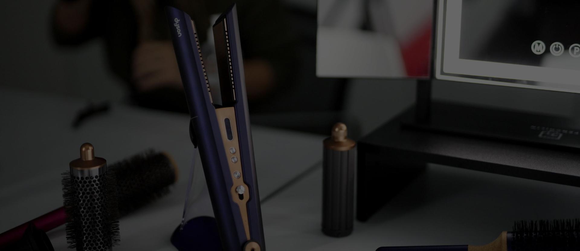 Model and stylists using Dyson Supersonic hairdryer flyaway attachment to create a sleek low pony tail