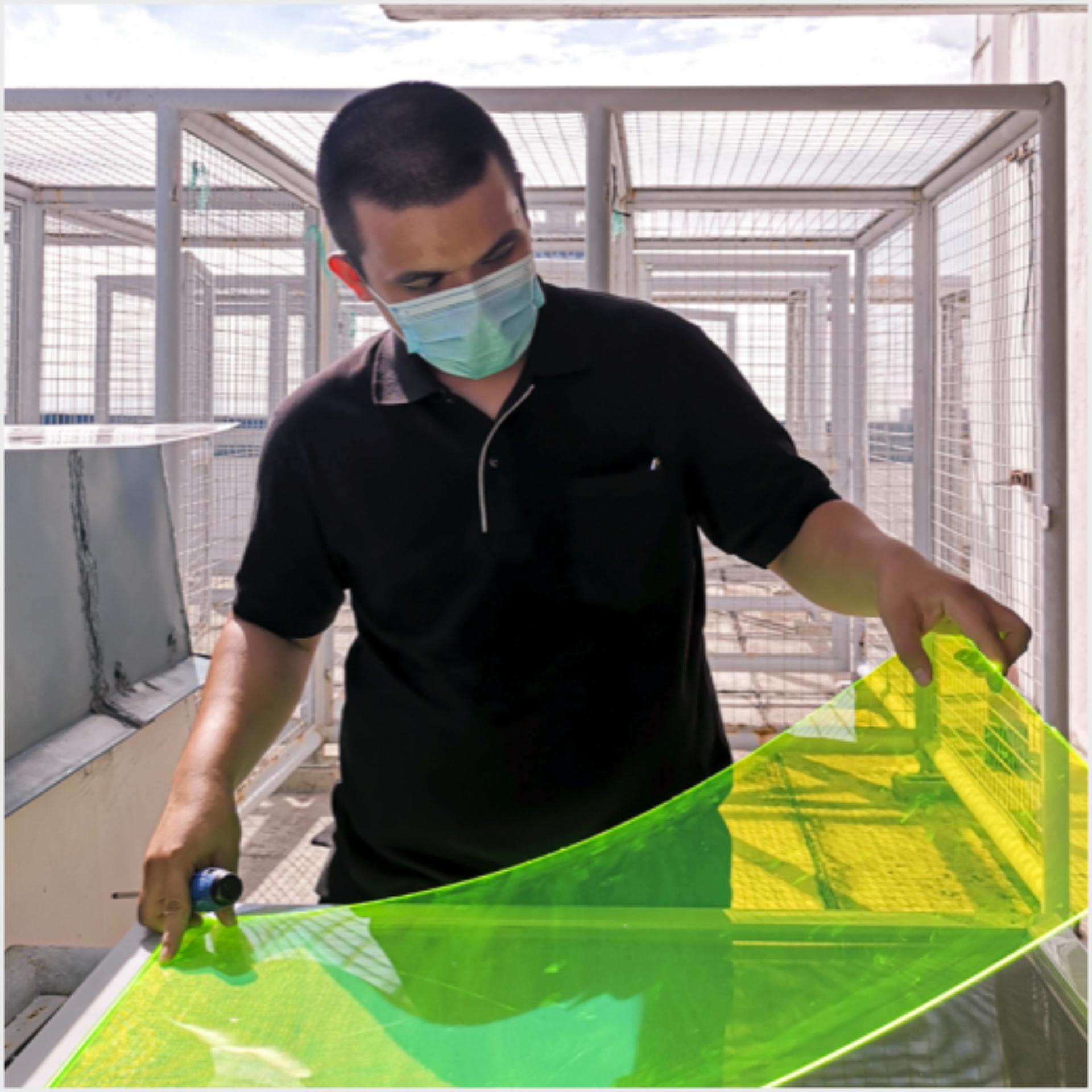 Mees hoidmas läbipaistvat rohelist ümbertöödeldud materjalist paneeli