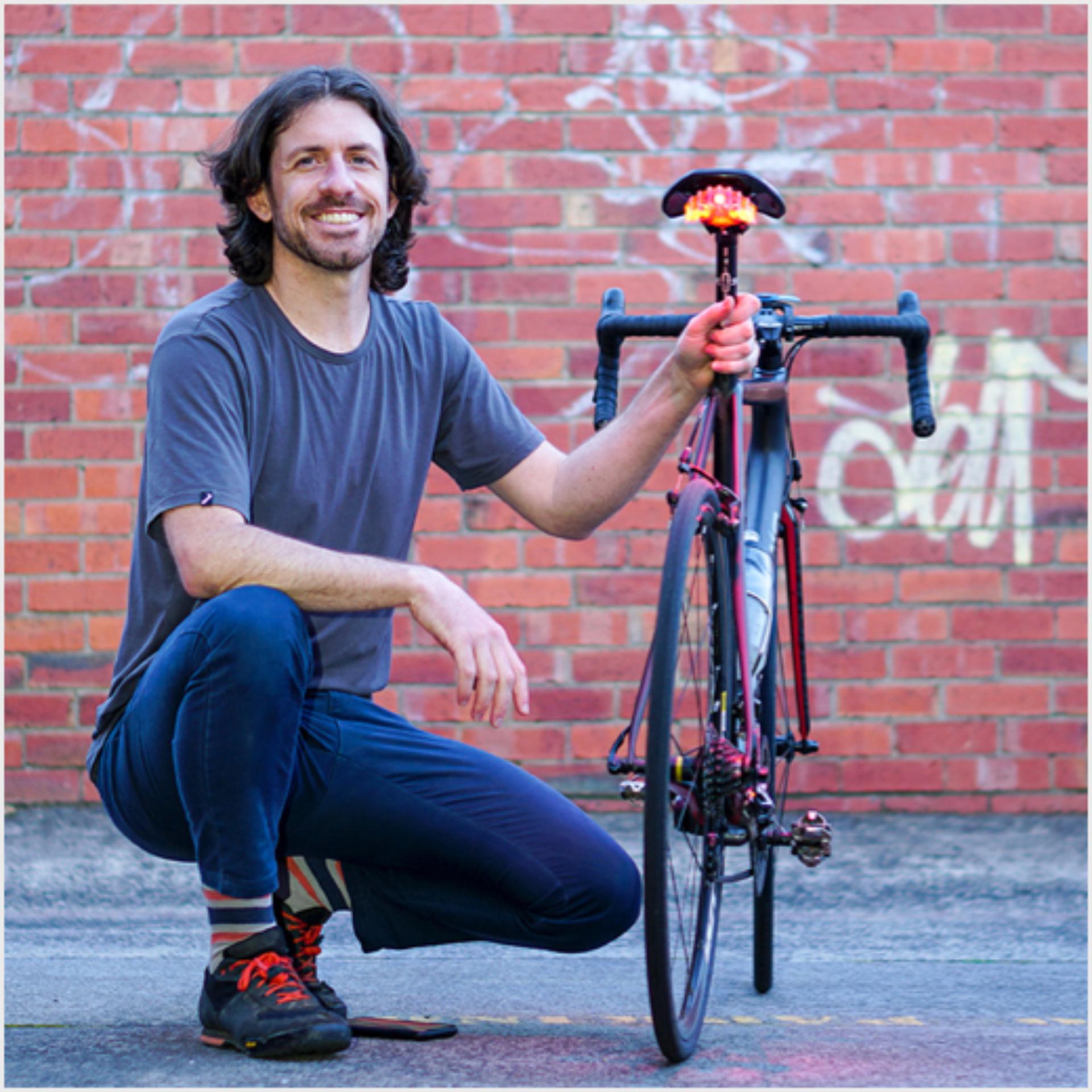 Mees põlvitamas tellisseina ees jalgratta kõrval