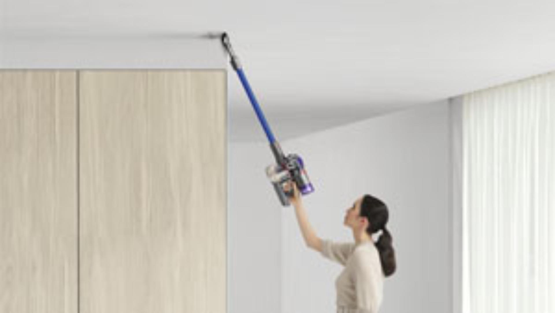 Woman cleaning up high with Dyson V8 vacuum