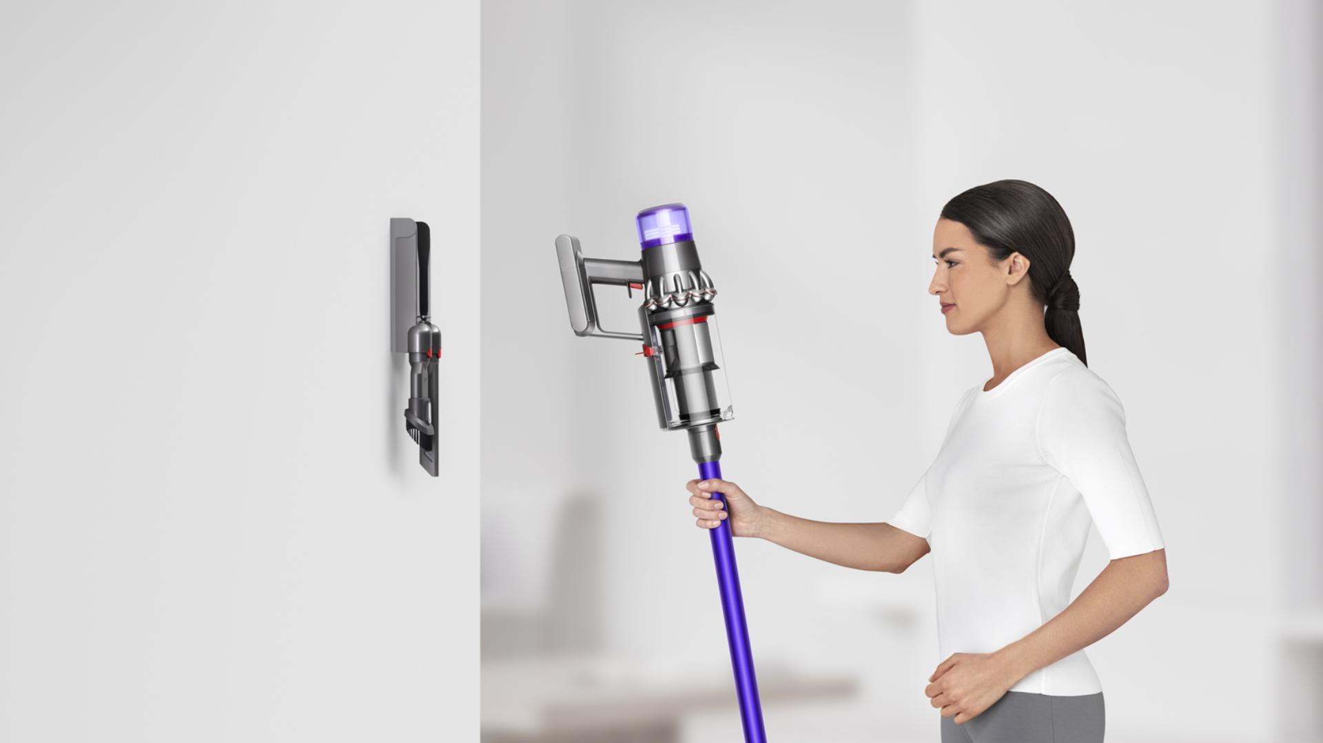 Woman placing Dyson V11 vacuum into wall charging dock