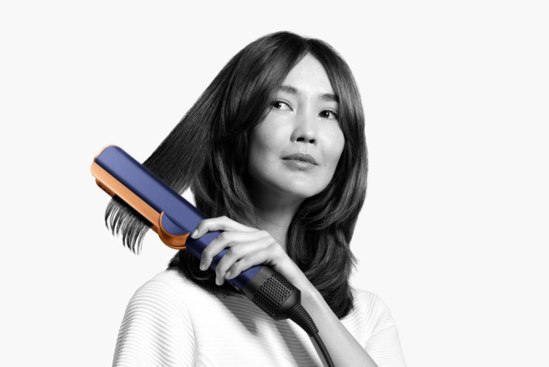 Woman using Dyson Airstrait straightener on her hair 