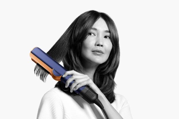 Woman using Dyson Airstrait straightener on her hair