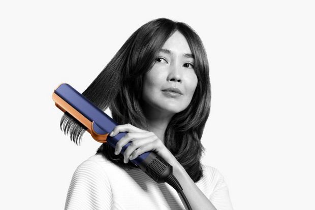 Woman using Dyson Airstrait straightener on her hair 