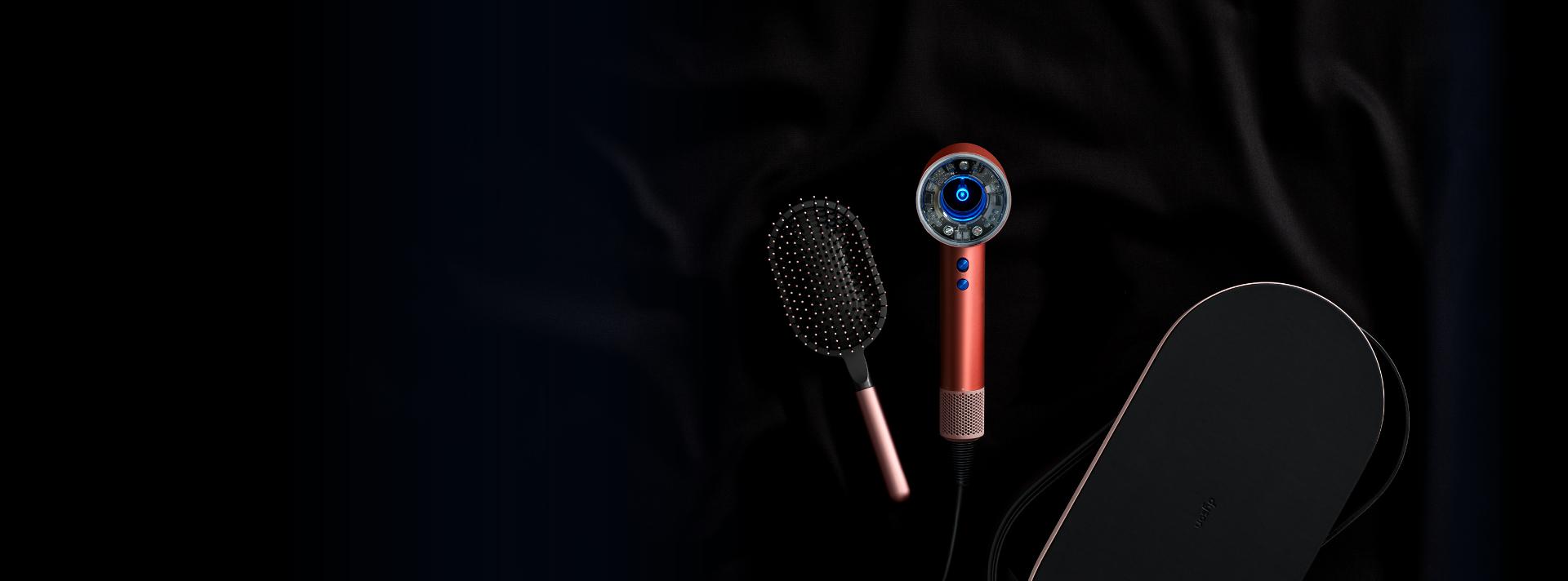 The Dyson Supersonic hair dryer beside its attachments and presentation case
