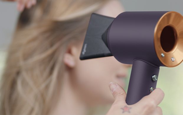 Woman using the Dyson Supersonic hair dryer