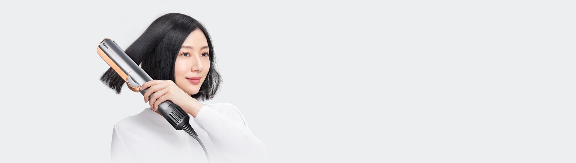 兩位模特兒正使用 Dyson Airstrait 二合一吹風直髮器。