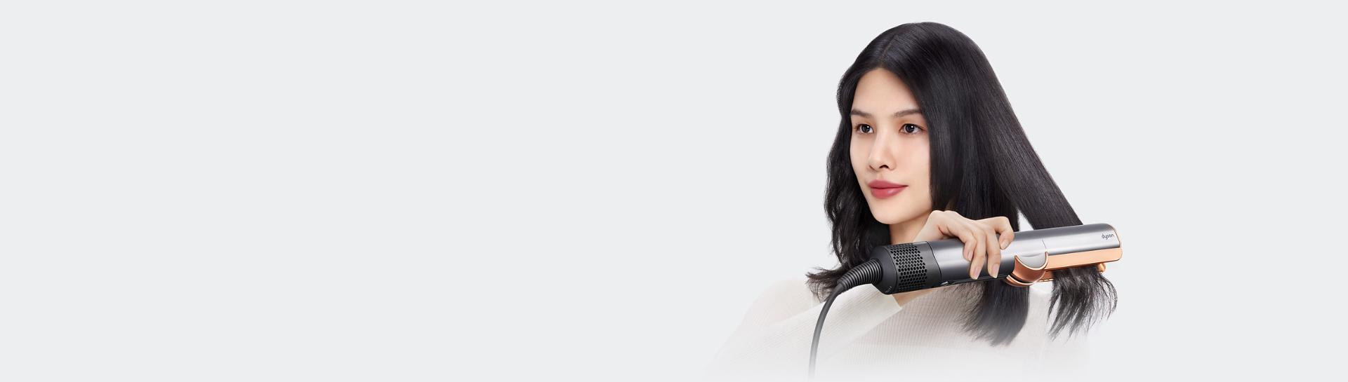 兩位模特兒正使用 Dyson Airstrait 二合一吹風直髮器。