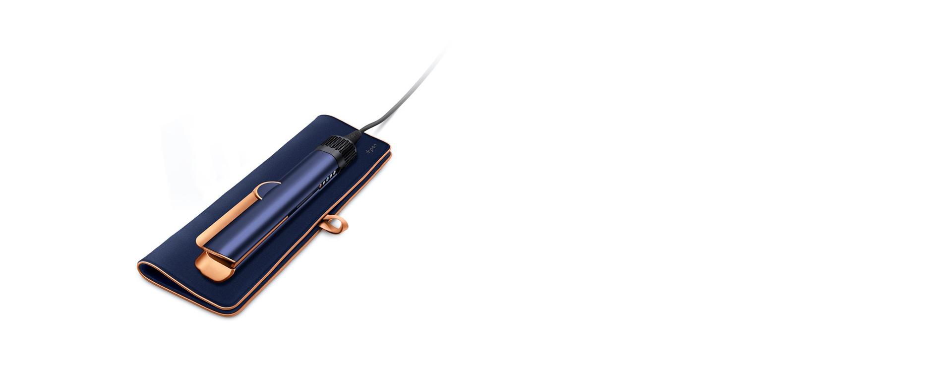 A Dyson Airstrait straightener resting on a travel pouch.