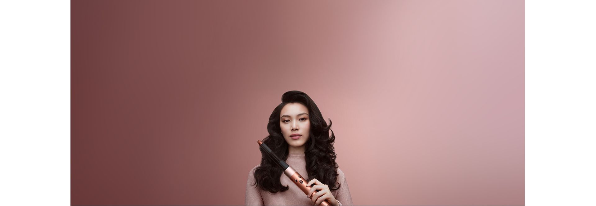 A model with brunette coily hair in a stretched blowout style holding the Dyson Airwrap i.d. multi-styler and dryer.