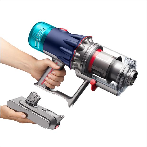 A hand is holding the V12s in one hand and the battery pack in the other hand.