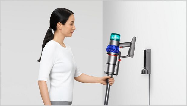 將Dyson吸塵機放於掛牆底座的女士