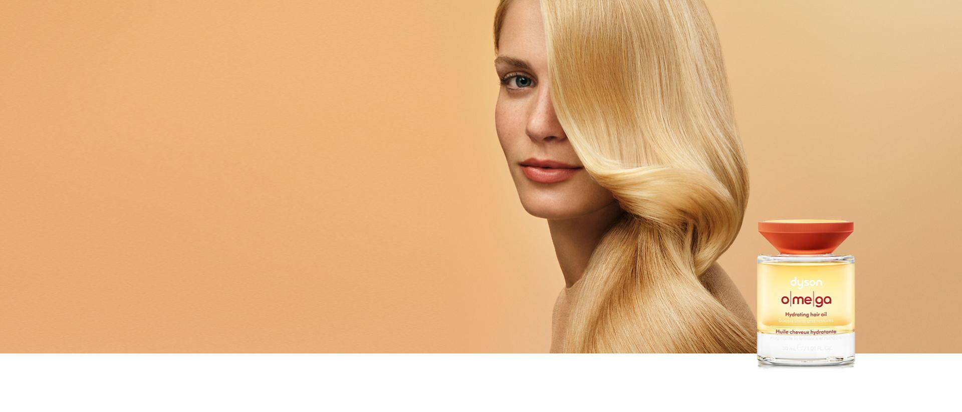 A curly haired model behind the Dyson Omega hair care range.